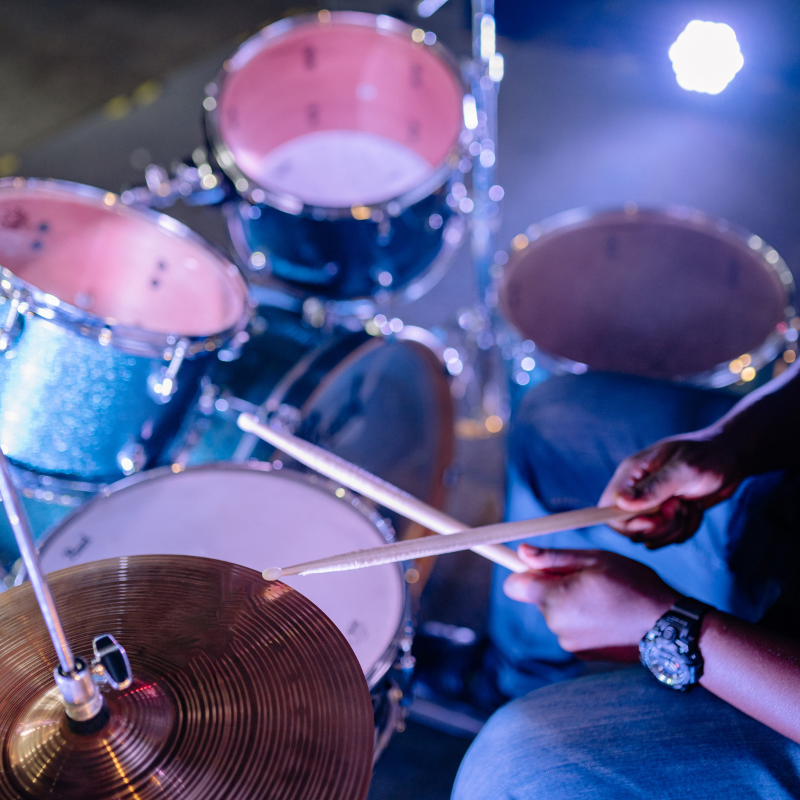 Drummer playing a drum set with a blue and pink color scheme.
