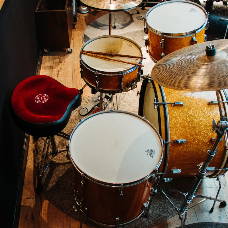 Drum set with various drums and cymbals on a wooden floor.