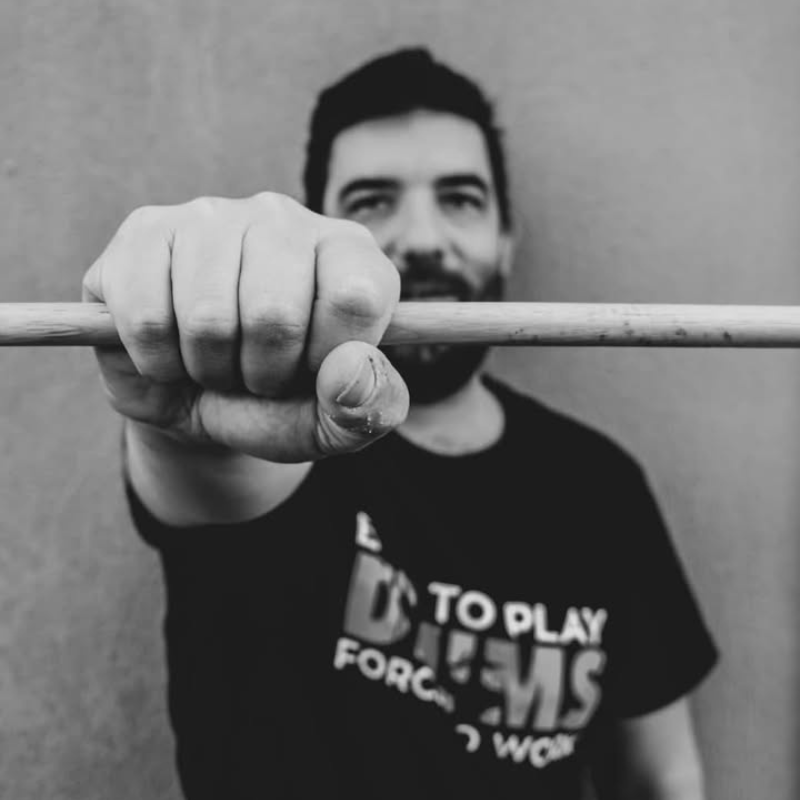 Man holding a barbell with a blurred face, wearing a t-shirt with text.