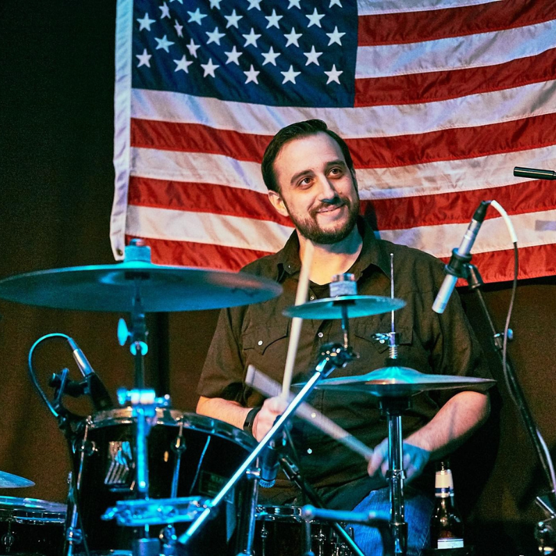 Man playing drums with an American flag in the background