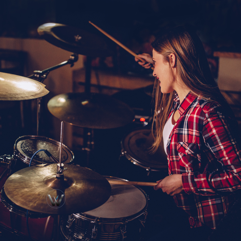 Person playing drums in a dimly lit room